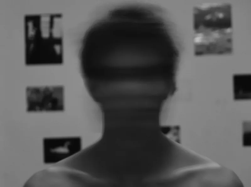 Black and white motion-blurred portrait of a person seen from behind in front of a photo gallery wall