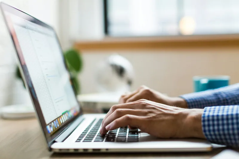 Close-up view of hands typing on a modern laptop keyboard