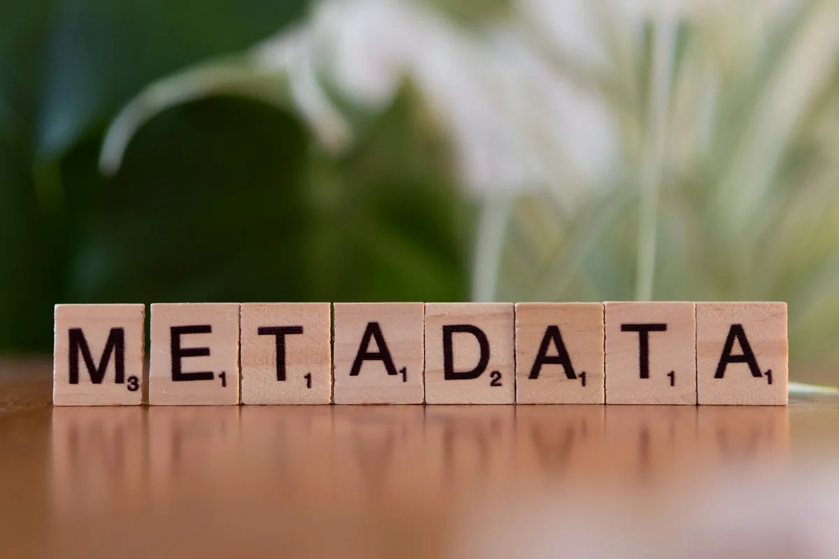 Wooden Scrabble letter tiles spelling out the word METADATA on a wooden table
