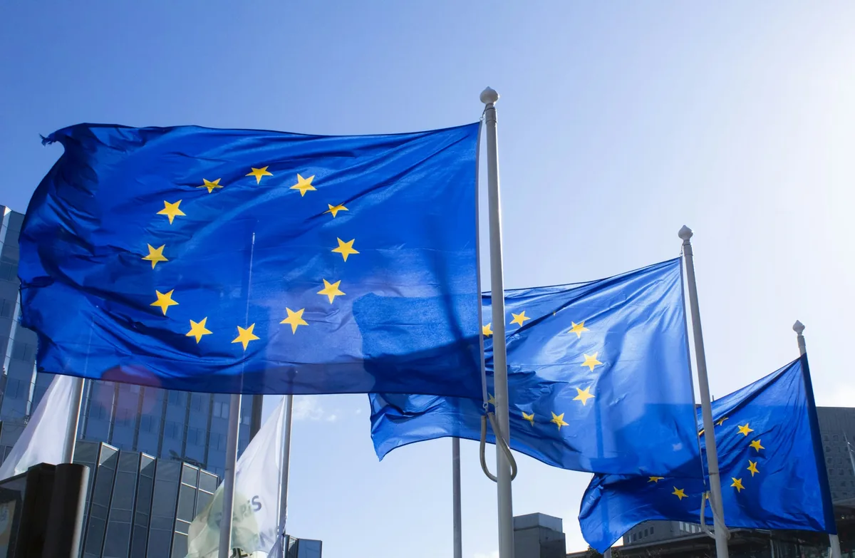 European Union flags fluttering on flagpoles against a clear blue sky