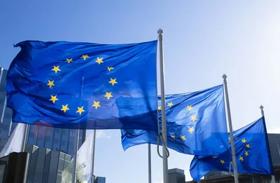 European Union flags fluttering on flagpoles against a clear blue sky