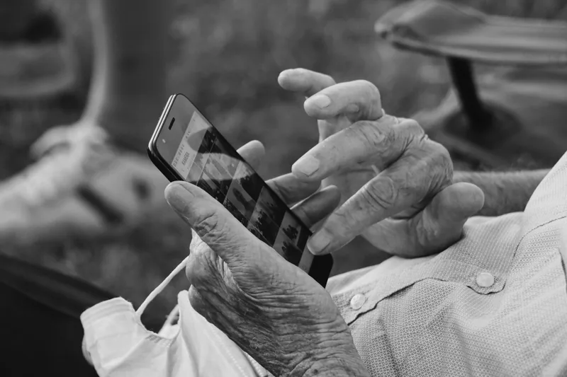 Black and white photo of an elderly person's hands using a smartphone